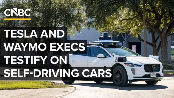 Une voiture autonome Waymo blanche garée dans une rue avec une rangée de capteurs sur le toit.