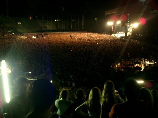 Bruce Springsteen sings into a microphone while playing an acoustic guitar during a concert in Munich.