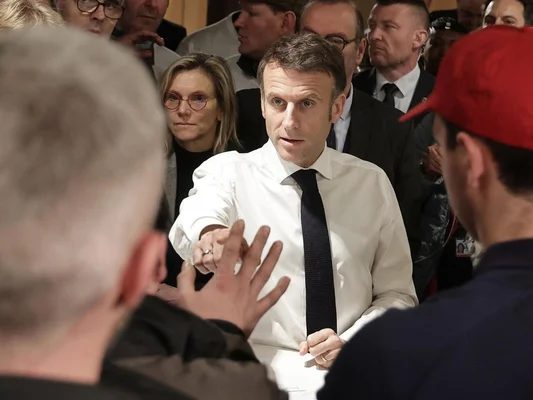 Emmanuel Macron tend la main vers quelqu'un dans la foule
