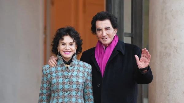 Jack Lang et Monique lors de leur rencontre, devant une porte en bois.