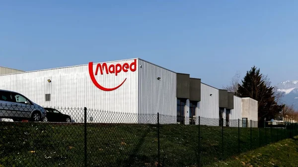 Usine industrielle Maped avec logo rouge et montagne en arrière-plan