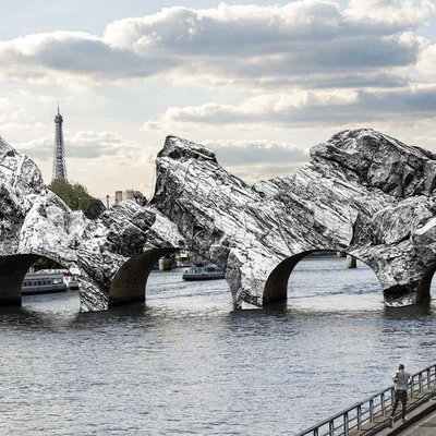 Vue d'un pont sculptural évoquant une grotte avec la tour Eiffel en arrière-plan.