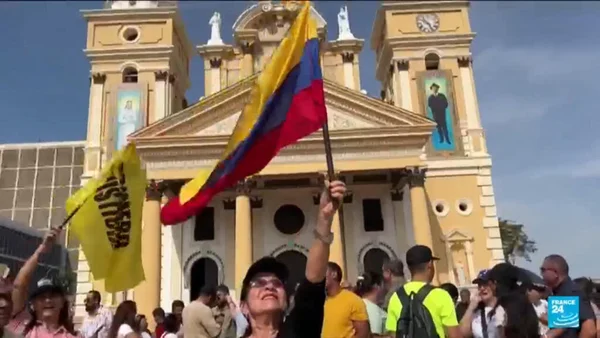 Foule devant une église tenant des drapeaux colombien et vénézuélien.