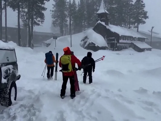 Randonneurs équipés de skis traversant un paysage enneigé près d'un bâtiment en bois après l'avalanche
