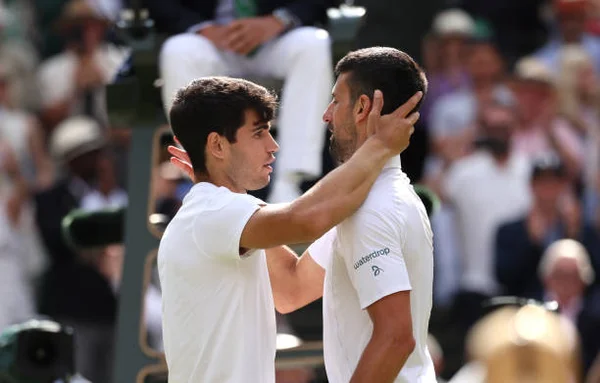 Carlos Alcaraz of Spain meets Novak Djokovic of Serbia at the net following victory in the Gentlemen's Singles Final during day fourteen of The...