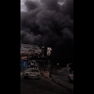 Une colonne de fumée s'élève d'une zone boisée et résidentielle près d'un château d'eau.