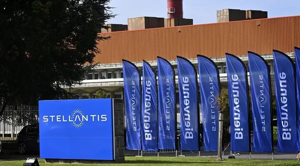 Panneau d'accueil et drapeaux Stellantis devant l'entrée d'un site industriel du groupe.
