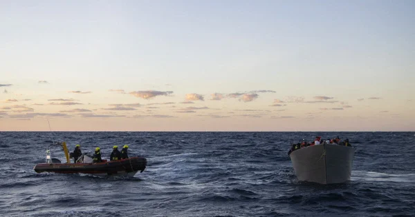 Un canot pneumatique transportant quatre migrants croise un navire plus grand sur la mer Méditerranée.
