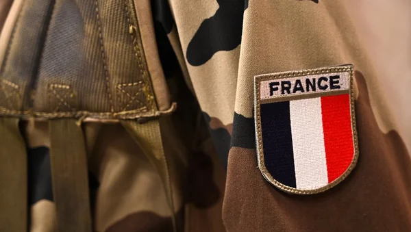 Deux soldats en opération dans un cadre extérieur, identifiables à leur insigne national aux couleurs tricolores.