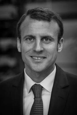 Portrait d'Emmanuel Macron en costume sombre et cravate, souriant.