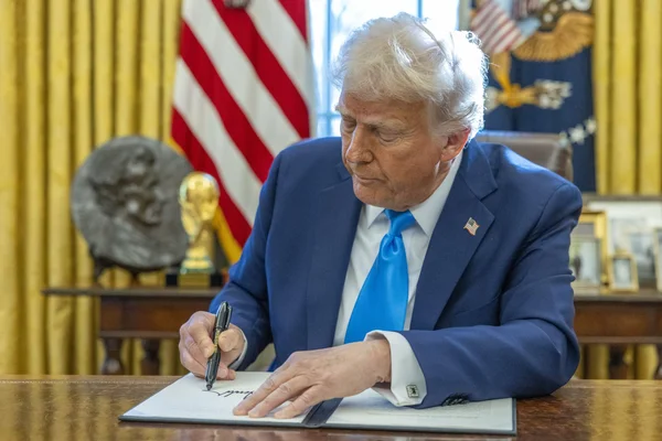 Donald Trump signant un document officiel à son bureau.