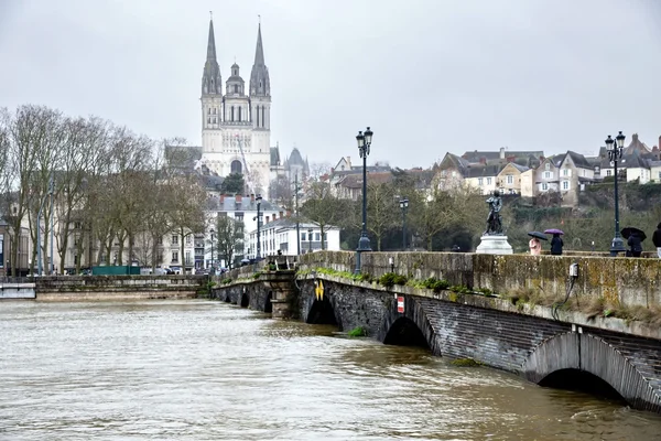 Un pont de pierre avec une statue surplombe la Maine, avec la cathédrale en arrière-plan.