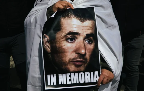 Un participant tient une affiche 'IN MEMORIA' à l'effigie d'Yvan Colonna lors d'une cérémonie.