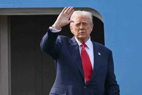 Une personne en costume saluant devant une structure bleue.