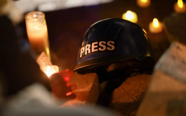 Un gilet de presse bleu posé au milieu de documents et de peinture rouge.