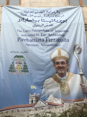 Une bannière de bienvenue avec le portrait de Mgr Pierbattista Pizzaballa, archevêque, et les armoiries du Patriarcat latin de Jérusalem.