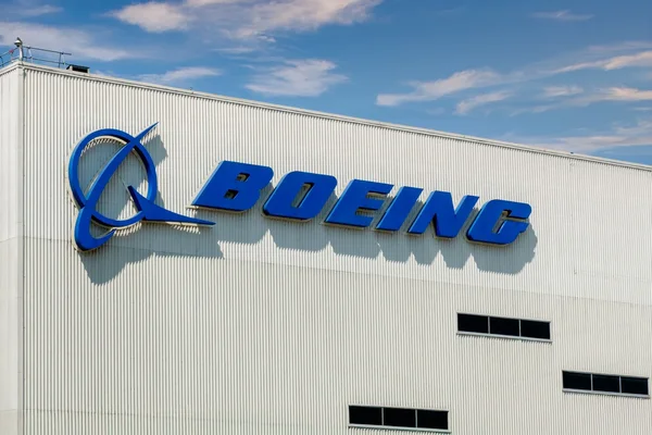 Façade d'un bâtiment industriel blanc avec le grand logo Boeing bleu.