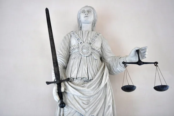 Statue allégorique de la Justice, tenant une épée et une balance, symbolisant le procès.