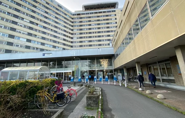L'entrée vitrée d'un bâtiment du CHU de Bordeaux, avec des vélos et des passants.