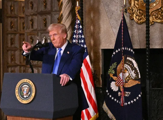 Discours officiel depuis le podium présidentiel devant le drapeau américain dans une salle boisée.
