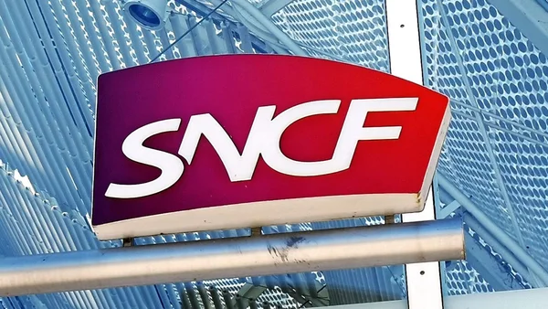 Enseigne SNCF rouge et violette montée sur une structure métallique perforée.