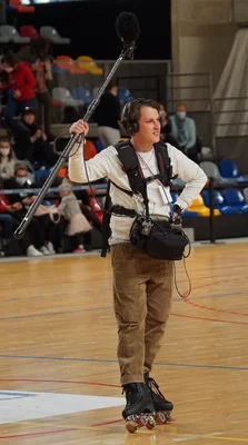 Reportage de Quotidien à René Tys en 2021 : un journaliste équipé d'un micro perche sur un terrain de sport.