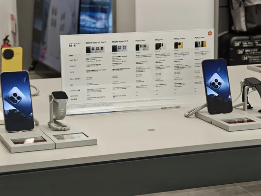 Vitrine de smartphones Xiaomi et montres connectées au Xiaomi Store avec une planche d'information en arrière-plan.