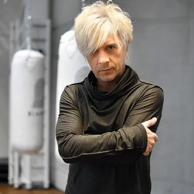 Nicola Sirkis croisé les bras devant des sacs de frappe.