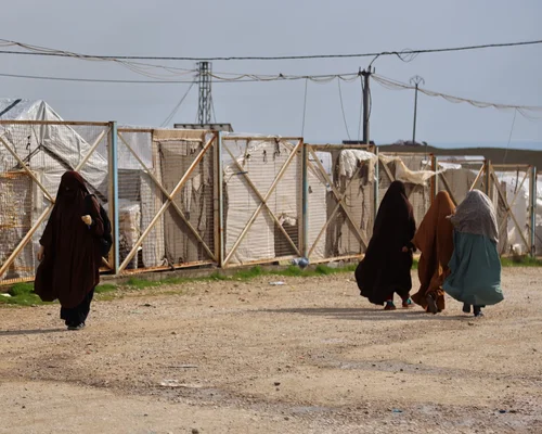 Vue aérienne d'un camp de réfugiés dense avec des tentes et des réservoirs d'eau rouges.
