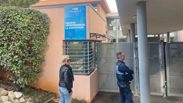 L'entrée du collège La Guicharde à Sanary-sur-Mer, avec une femme en veste de cuir et un officier en uniforme près du portail.
