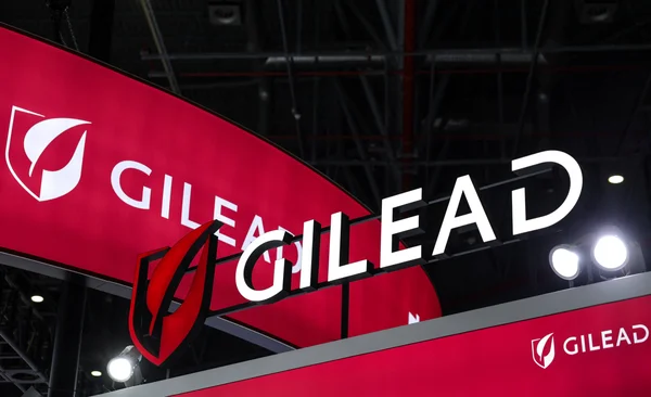Stand d'exposition intérieur avec plusieurs bannières rouges affichant le logo et le nom Gilead Sciences.
