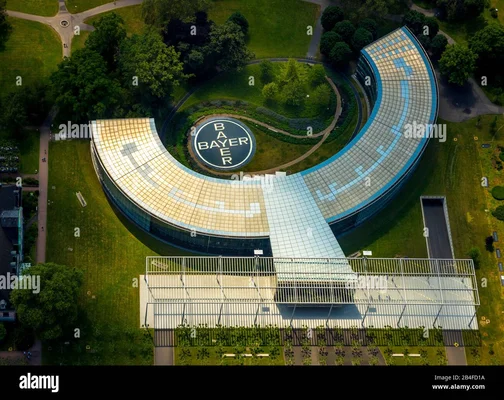 Vue aérienne du siège de Bayer AG à Leverkusen, avec son bâtiment circulaire au logo central et sa toiture vitrée.