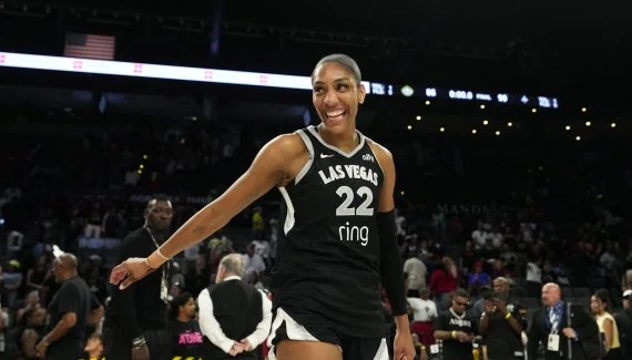 La joueuse des Aces de Las Vegas souriant et tenant un trophée devant son public.