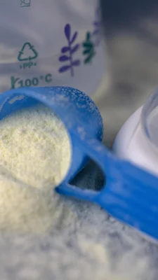 Une cuillère doseuse en plastique bleue remplie de poudre, probablement du lait infantile.