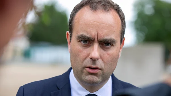 Sébastien Lecornu en costume cravate sur fond extérieur flou.