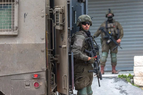 Deux soldats en uniforme olive positionnés dans une ruelle étroite en pierre