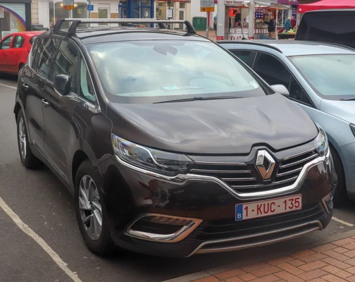 Un Renault Espace de couleur marron foncé stationné en ville, identifiable par sa plaque belge.
