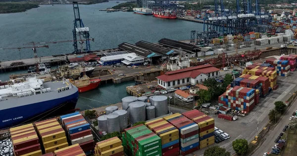 Vue aérienne du port avec le navire 'Dignity Leader' amarré et des conteneurs colorés.