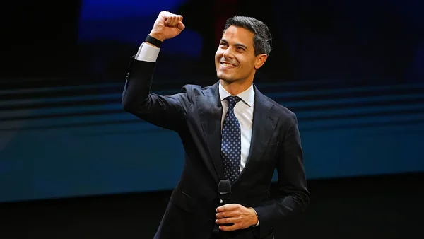 Rob Jetten sur scène avec un micro, levant le poing droit.