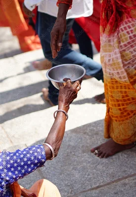 Une personne en vêtement orange tend un bol à une autre personne en tenue colorée près d'un temple hindou.