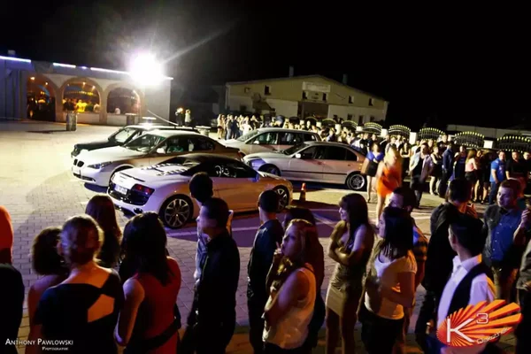 Attroupement nocturne près de voitures stationnées, évocation de la vie nocturne transfrontalière près de Strasbourg.