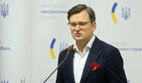 Le ministre ukrainien des Affaires étrangères s'exprimant devant un micro avec un décor aux symboles ukrainiens.