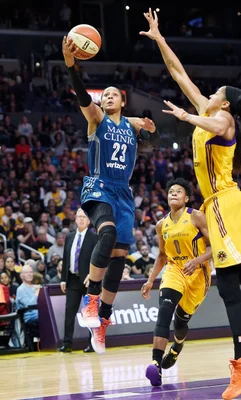 Action de jeu pendant un match WNBA avec une attaquante en bleu face à deux défenseuses en jaune.
