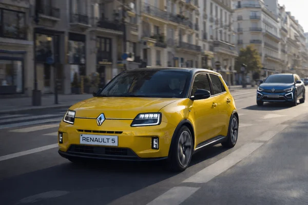 La Renault 5 électrique jaune, 100% électrique en Europe d'ici 2030, sur une rue urbaine avec des bâtiments classiques en arrière-plan.