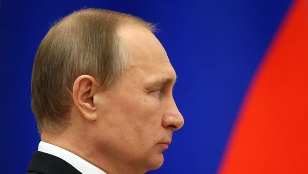 Vladimir Poutine vu de profil devant un fond aux couleurs bleu et rouge.