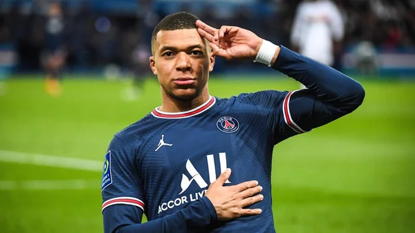 Kylian Mbappé en maillot du PSG saluant les supporters sur un terrain de football.