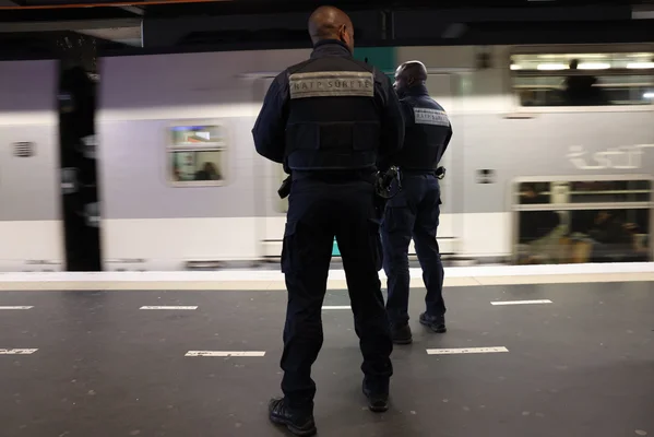 Des agents de sûreté de la RATP en uniforme patrouillent sur un quai de métro.