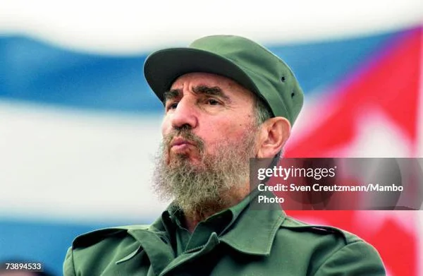 Un homme barbu portant une casquette militaire verte et un uniforme.