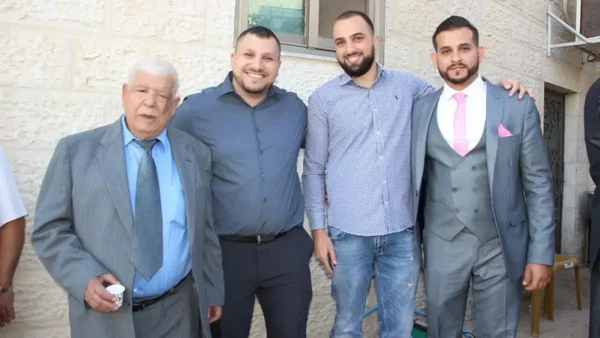 La famille d'Omar Assad se tient devant un bâtiment en pierre.