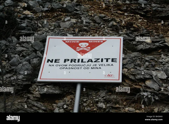 Signalisation de danger de mines devant des habitations inachevées en Croatie, témoignant des séquelles du conflit.